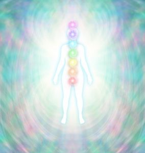 Chakra Energy Balancing  -  Soft pastel colored energy field around a white female silhouette with a turquoise glow, with seven chakras aligned centrally from crown to root